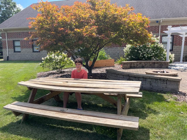 Student sitting on newly refurbished picnic table bench