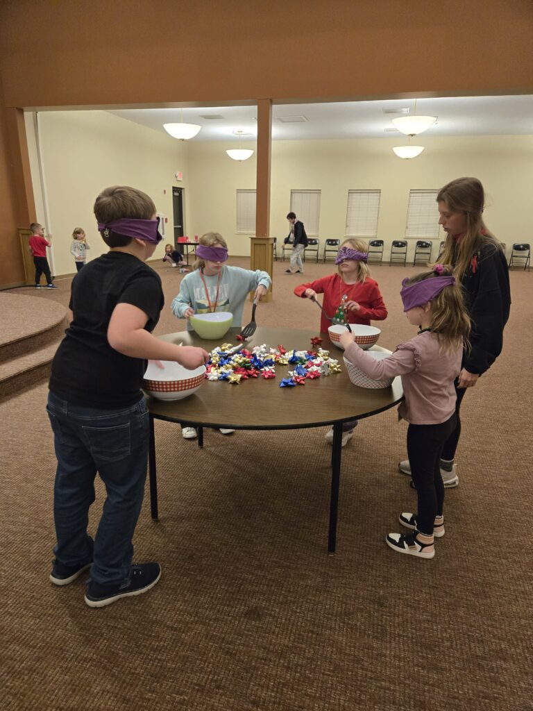 four person game of blindly scooping bows into bowls with spatulas